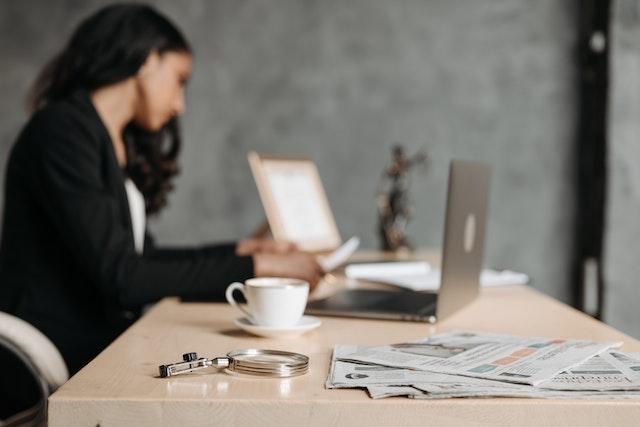 woman in formal clothing sitting at a desk and looking through paperwork