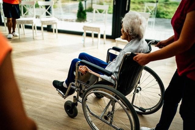an elderly person in a wheelchair being pushed by someone
