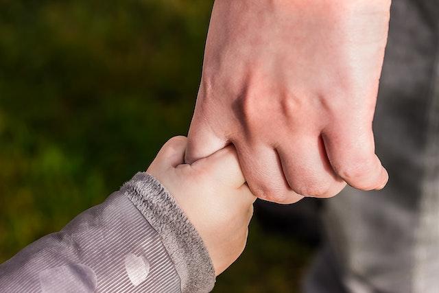 a child's hand grasping an adult's pointer finger