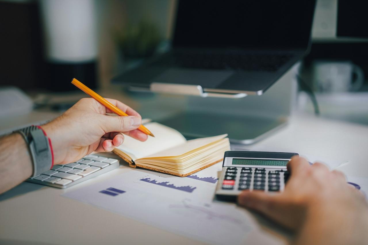 a person holding a pencil while using a calculator