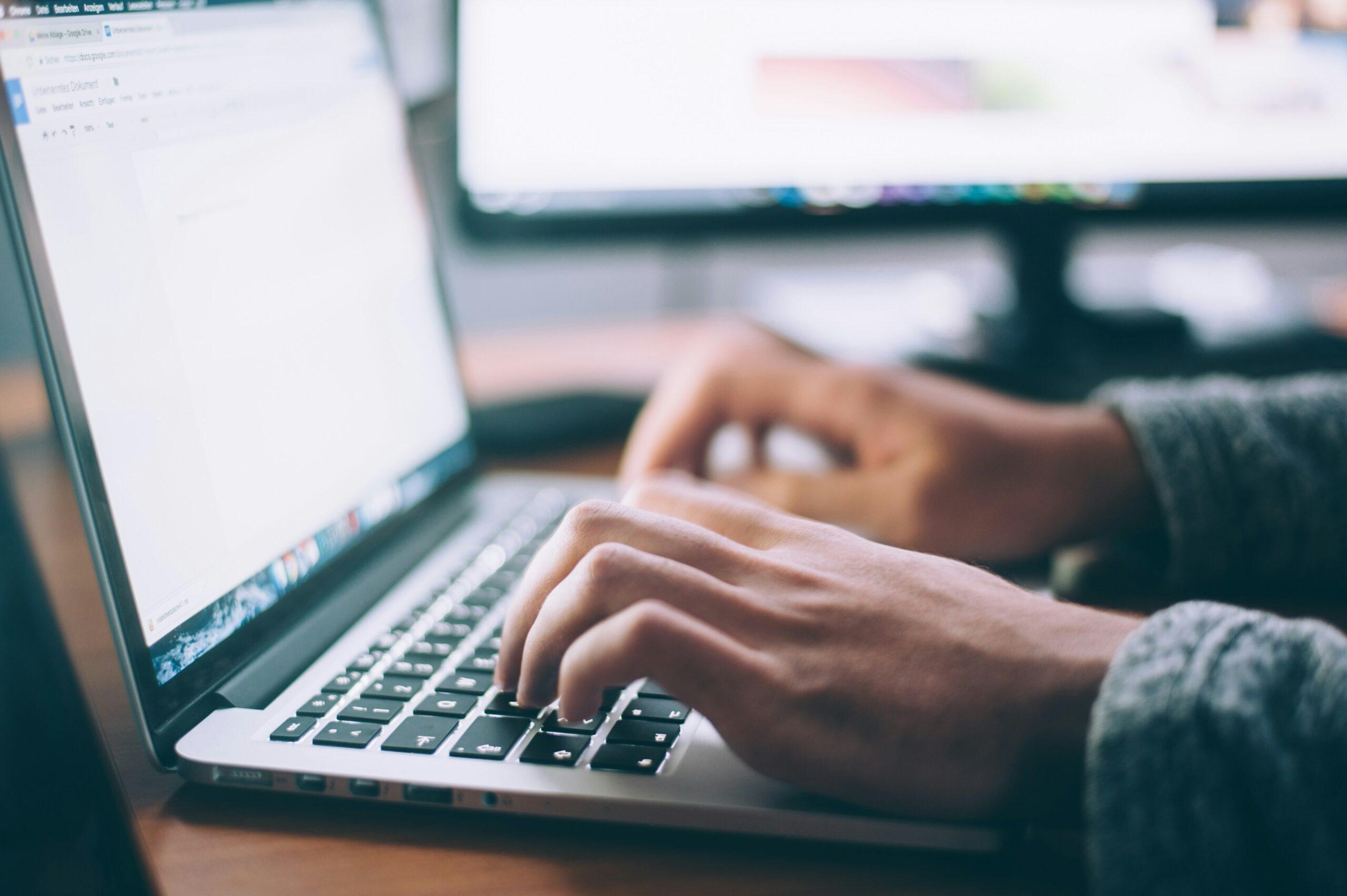 a close-up of a person's hands as they type on a laptop